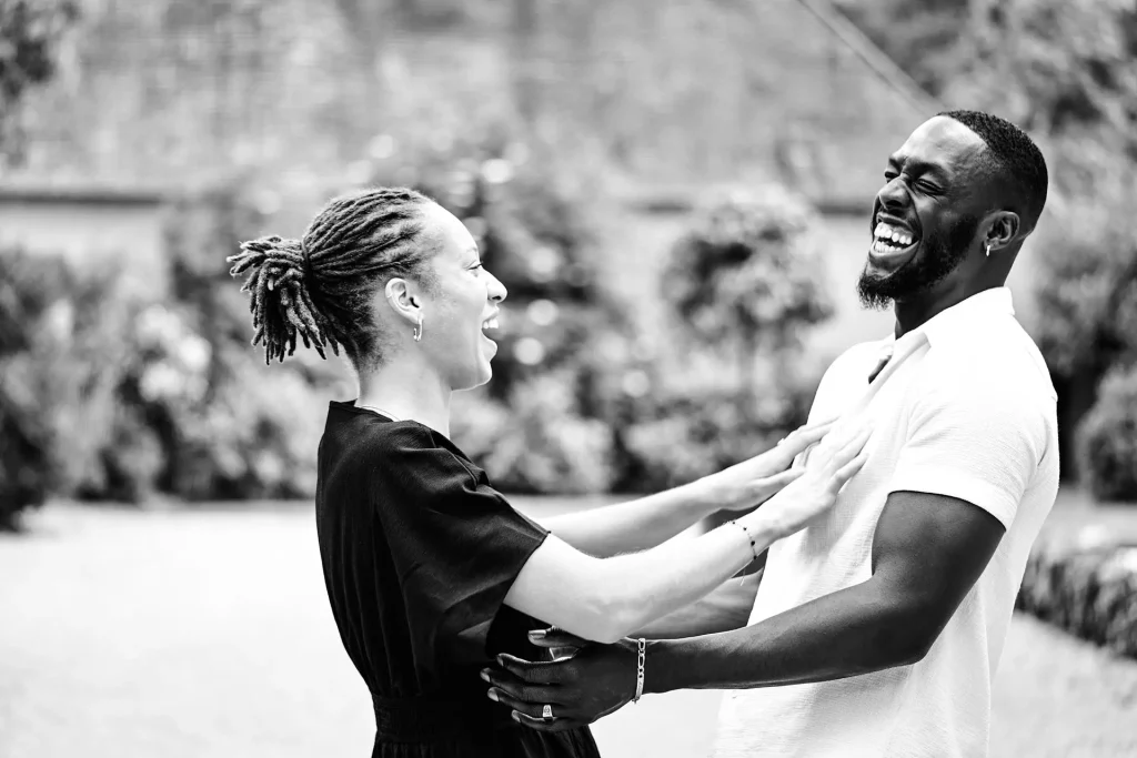 Portrait en noir et blanc d'un couple en extérieur, ils sont face à face et rient ensemble