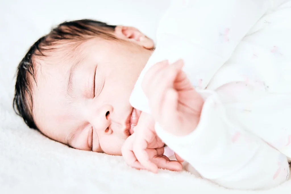 Bébé allongé sur le coté, photo zoom sur son visage et ses mains