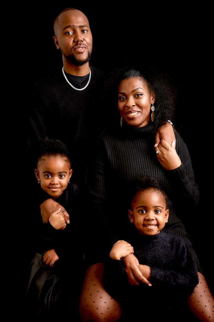 Portrait de famille au studio, fond noir, les parents et deux petites filles